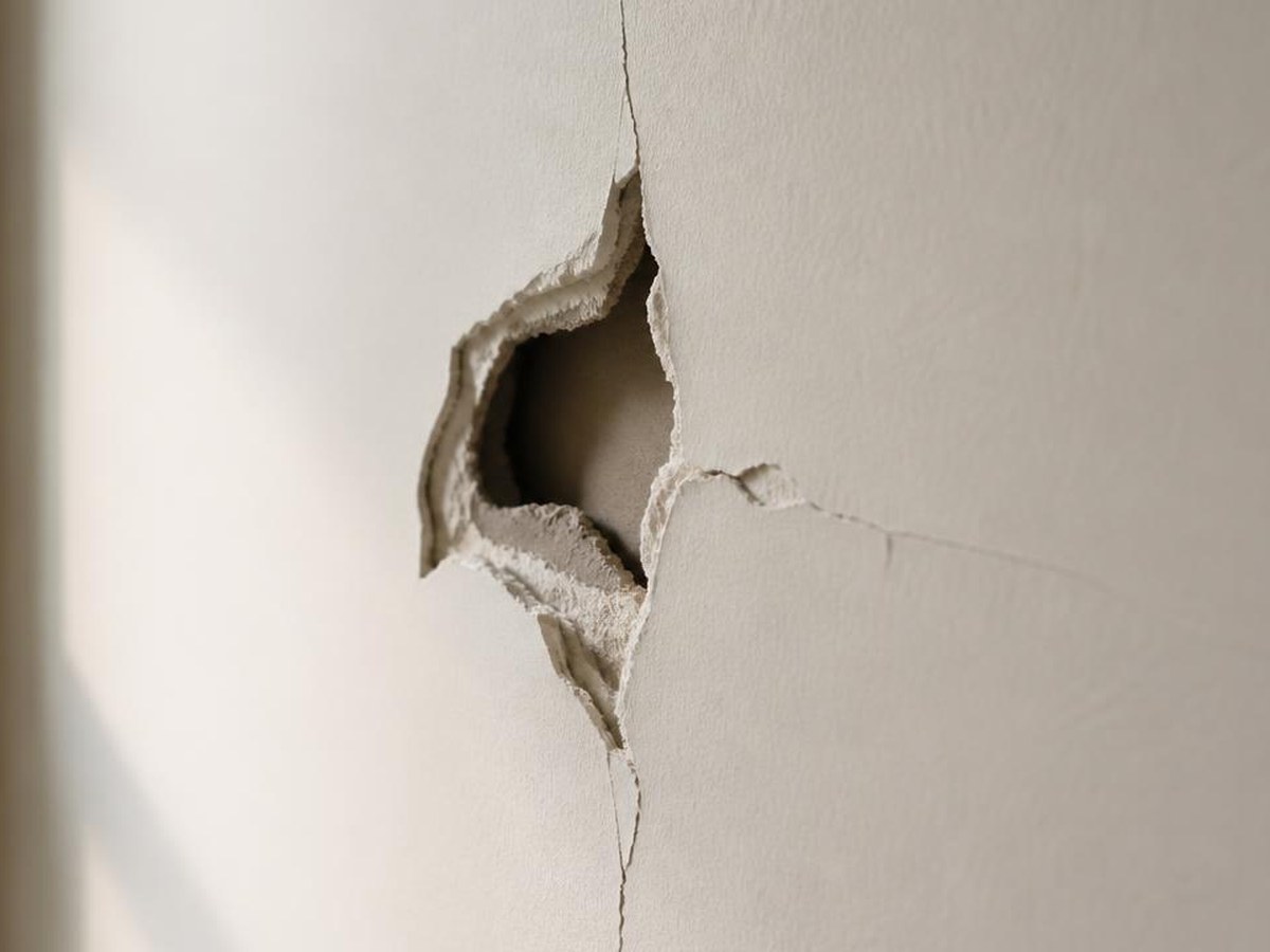 Plaster wall with impact damage and cracking before repair